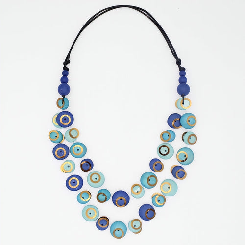 A double-strand necklace featuring blue and turquoise evil eye beads with gold accents, suspended on a black cord, shot against a plain white background.