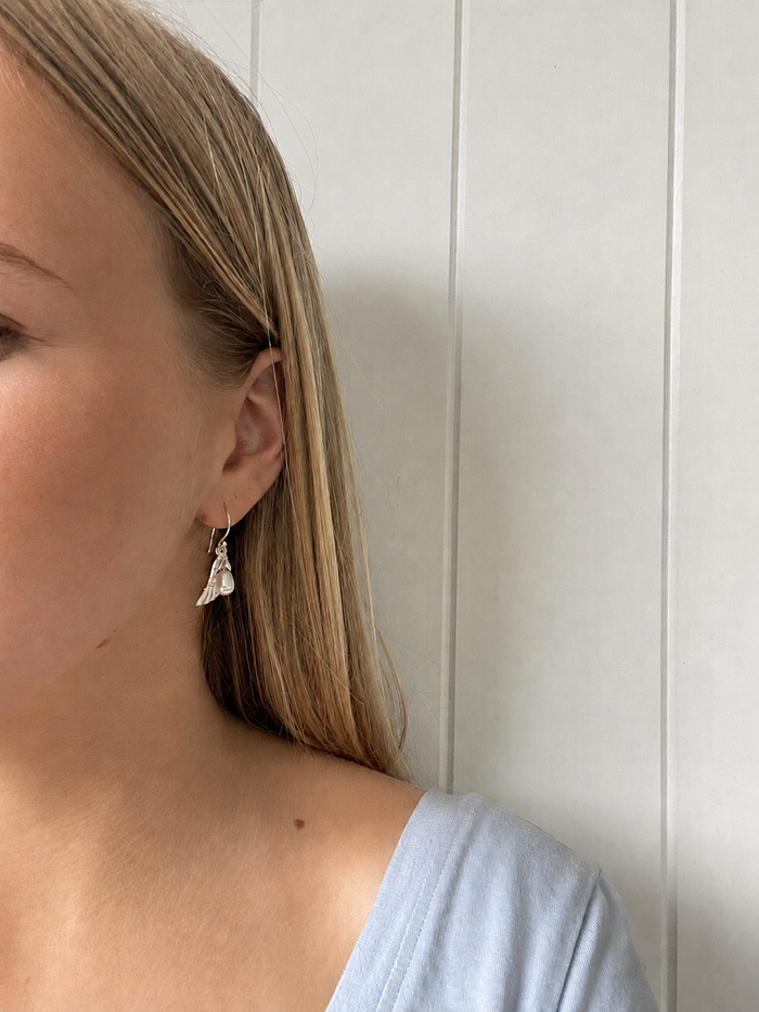 Close-up of a model wearing Angel Wing Earrings Silver with a delicate pearl drop.