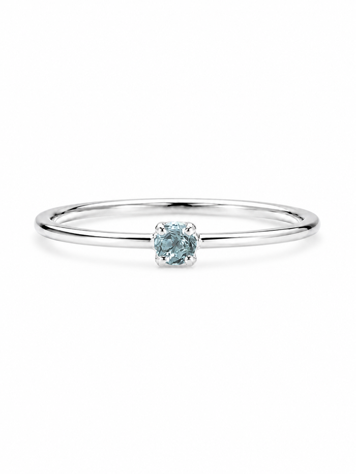A delicate sterling silver ring featuring a single round-cut light blue gemstone in a prong setting