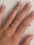 A silver dainty ring with a topaz light blue stone.