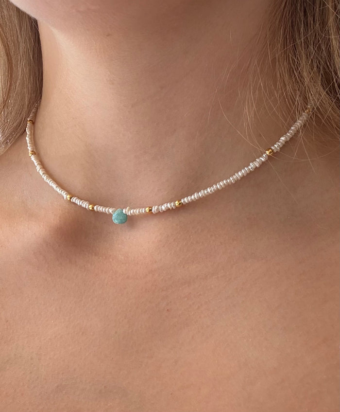 Necklace with a blue gemstone worn by a person