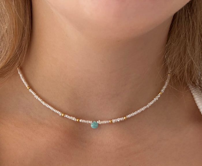 Necklace with a turquoise bead worn by a person