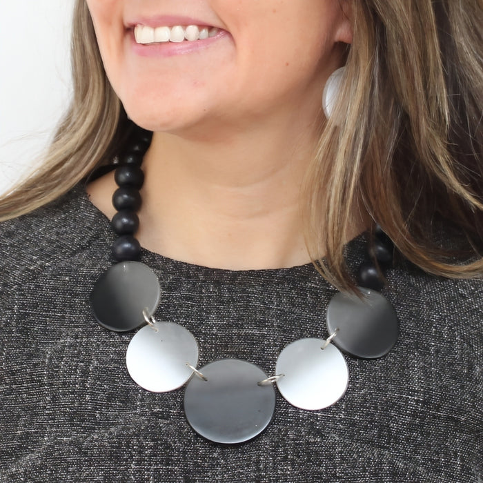 Necklace with black and silver circular pendants worn by a person