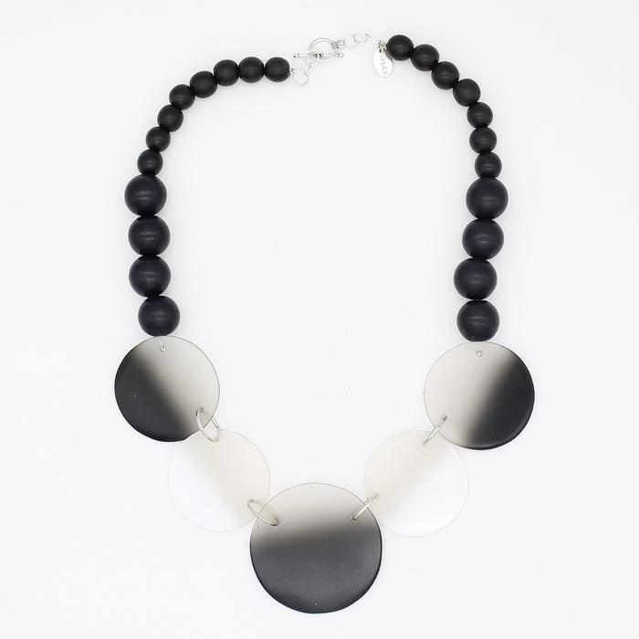 Necklace with black beads and round metallic discs on a white background
