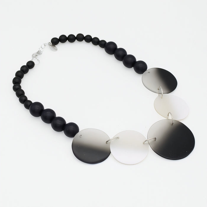 Necklace with black beads and gradient disc pendants on a white background