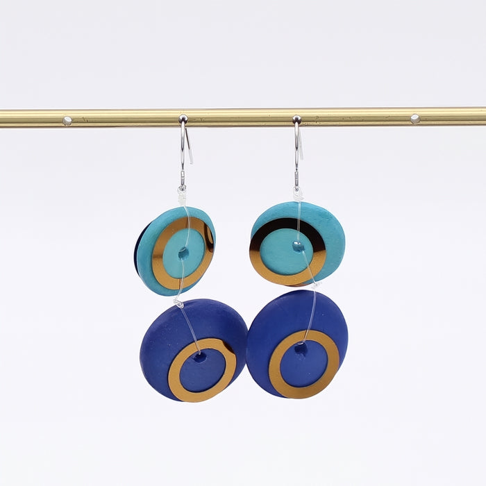 Pair of earrings with blue and gold circular design on a white background