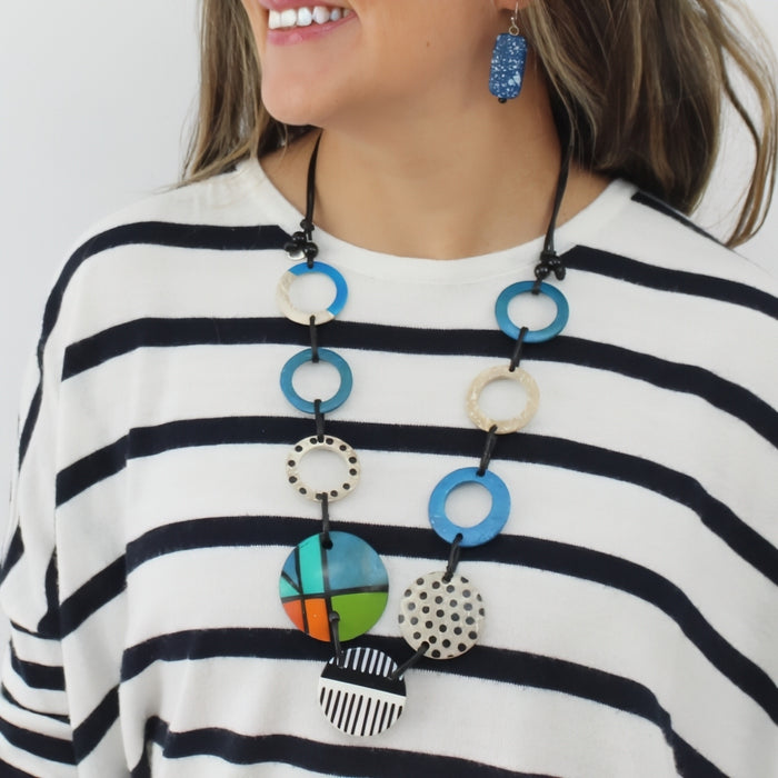 Woman wearing a colorful necklace with geometric pendants on a white background