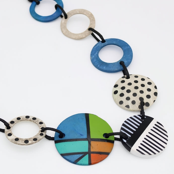 Colorful necklace with various circular pendants on a white background