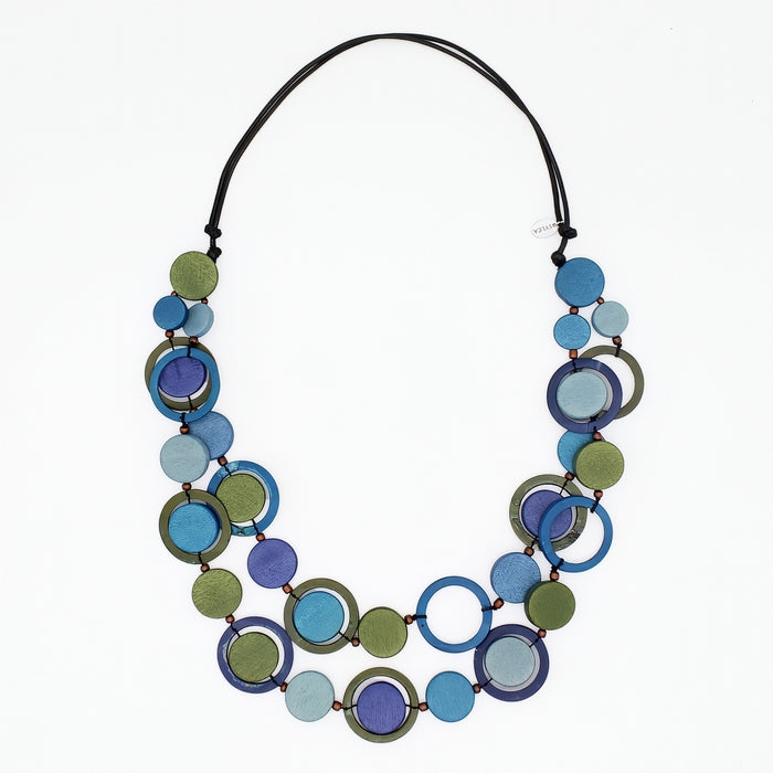 A multi-strand statement necklace featuring overlapping circular discs in shades of blue, purple, green, and light blue, strung on a black cord, shown against a plain white background.