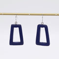 Navy blue square earrings hanging from a gold rod against a white background