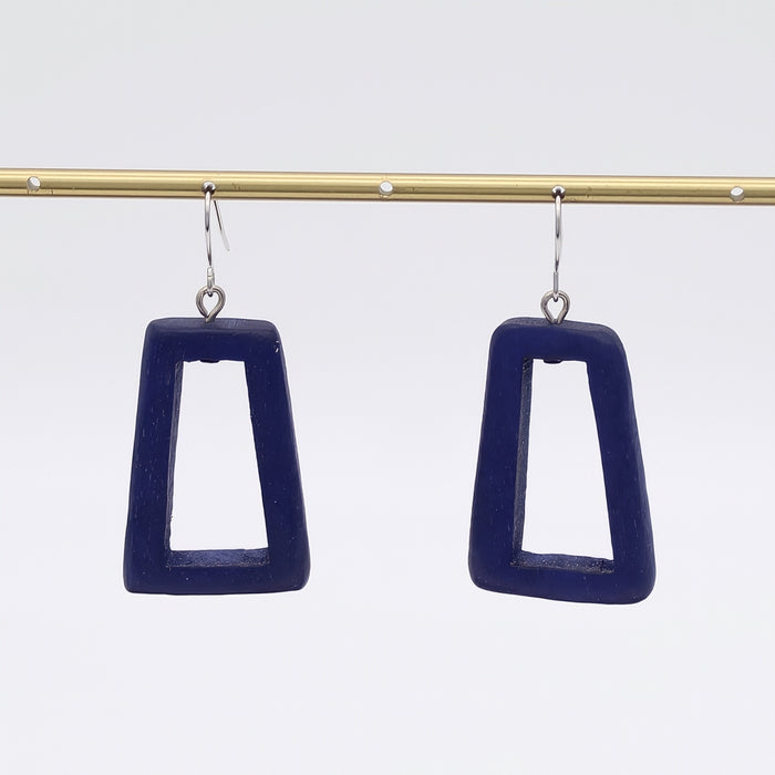 Navy blue square earrings hanging from a gold rod against a white background