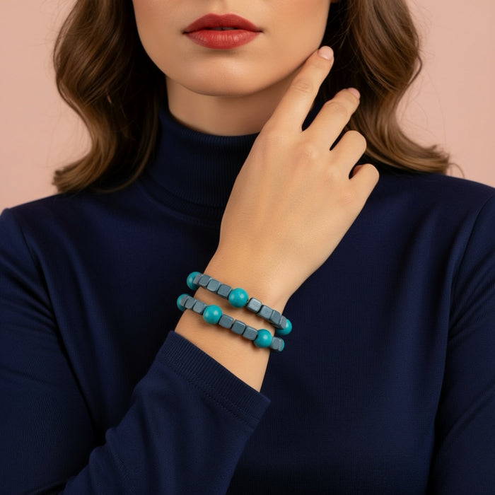 Woman wearing a blue turtleneck sweater with a close-up of her hand and turquoise bracelet.