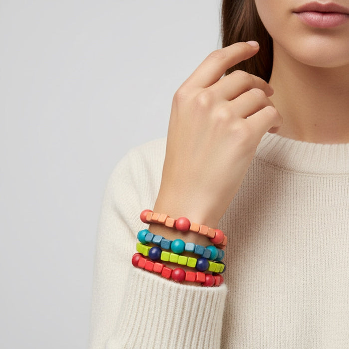 Person wearing a beige sweater with colorful beaded bracelets on a light gray background