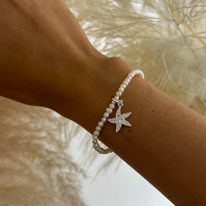 Pearl stretch bracelet with cubic zirconia starfish charm worn on wrist