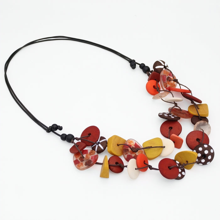 A handmade bohemian-style beaded necklace on a black cord, featuring a variety of colorful, organic-shaped beads in red, yellow, orange, white, and brown.