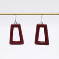 Pair of maroon square earrings on a gold rod against a white background