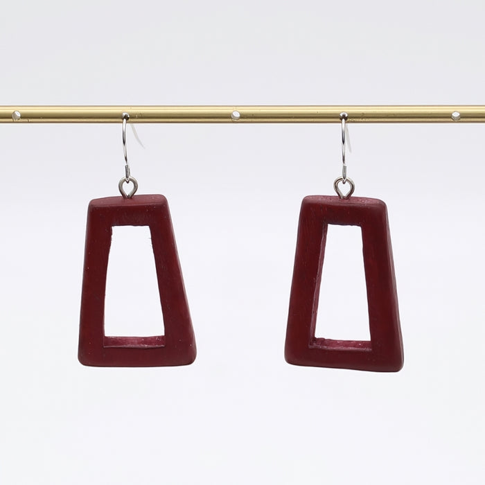 Pair of maroon square earrings on a gold rod against a white background