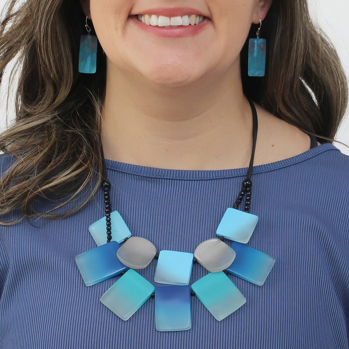 Woman wearing a blue and silver necklace with matching earrings on a white background