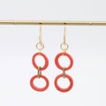 Pair of orange circular earrings with gold hooks on a white background