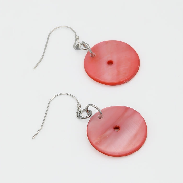 Pair of pink circular earrings with silver hooks on a white background