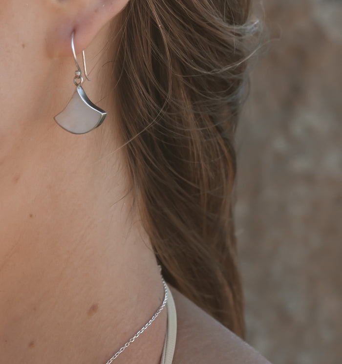 A pair of sterling silver earrings featuring large white mother of pearl shells shaped in a fan