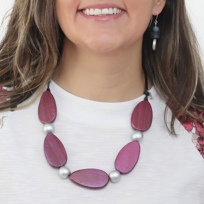 Woman wearing a necklace with pink and silver beads on a white background