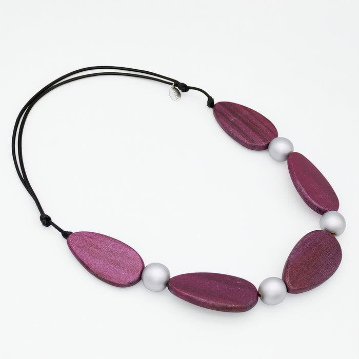 Necklace with purple wooden beads and white pearls on a white background