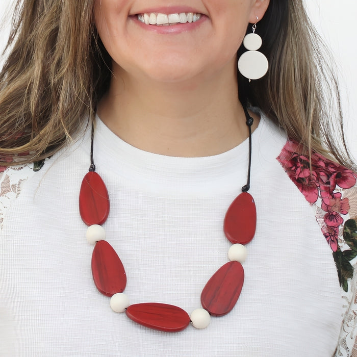 Woman wearing a red and white necklace with matching earrings on a white background