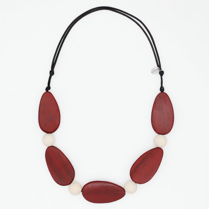 Necklace with red and white beads on a black cord against a white background