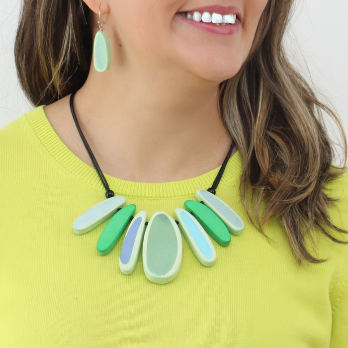Woman wearing a colorful necklace and earrings against a white background