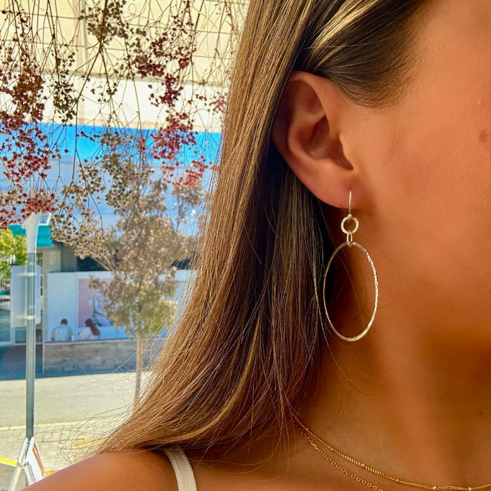 A person wearing hoop earrings made of sterling silver.