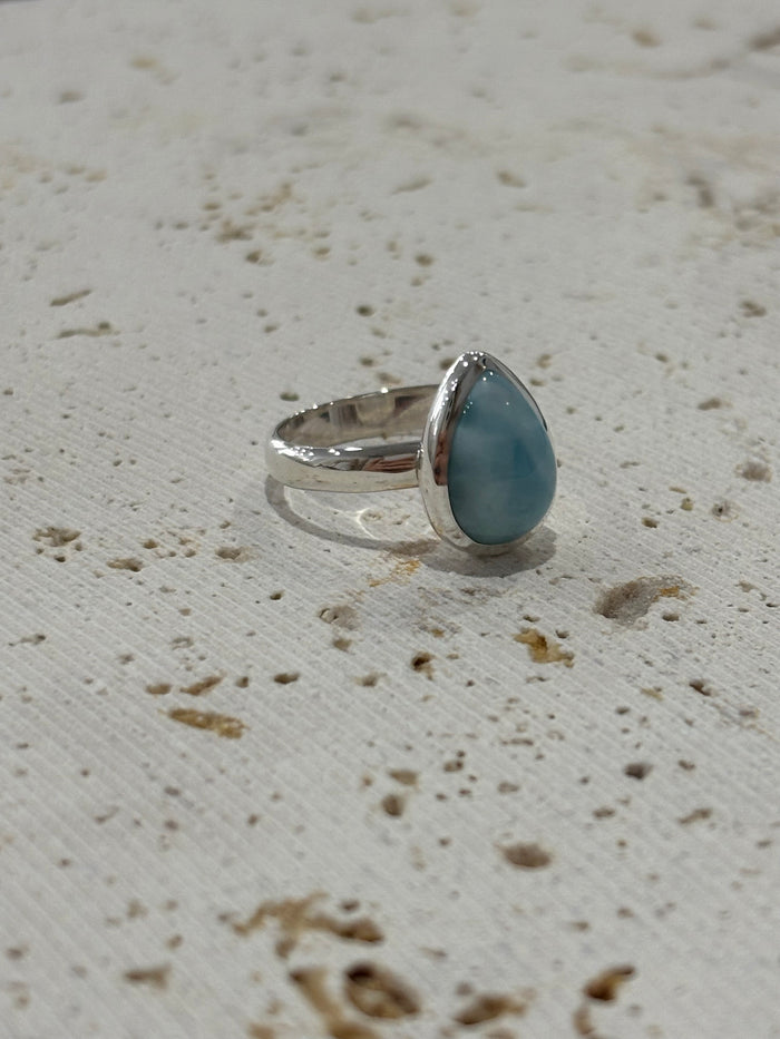 Silver ring with a Larimar stone on a textured beige surface