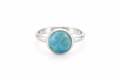 A silver ring with a round, polished light blue larimar stone in a bezel setting