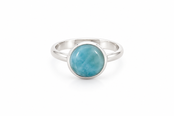 A silver ring with a round, polished light blue larimar stone in a bezel setting