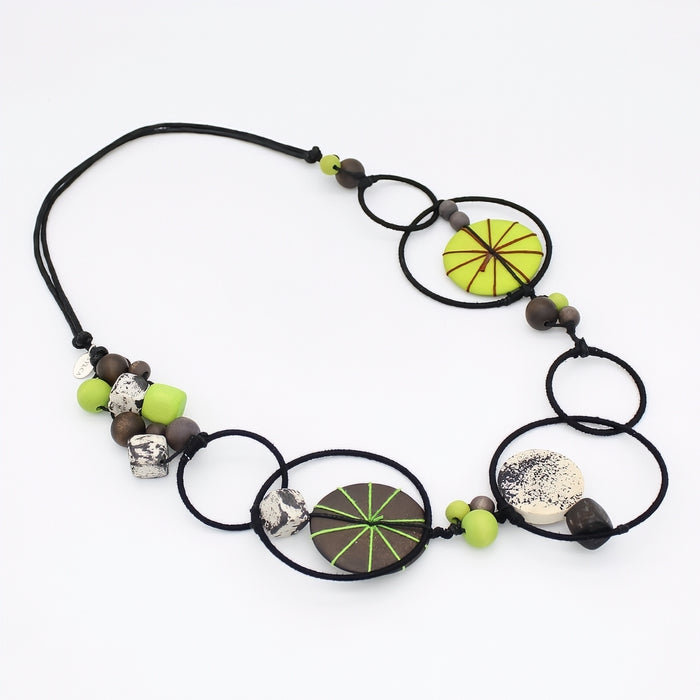 Necklace with circular black elements, green and brown beads on a white background