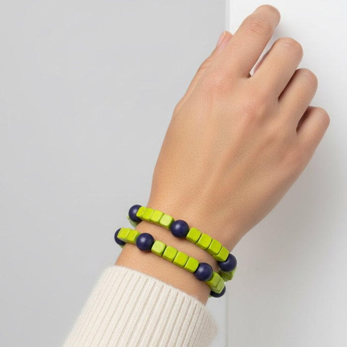 Hand wearing two beaded bracelets on a plain background
