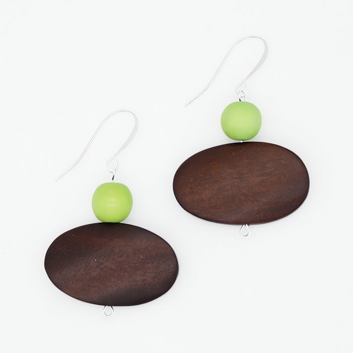 A pair of dangle earrings featuring oval dark brown wooden plates, a small light green bead, and silver-tone fishhook wires, displayed on a clean white background.