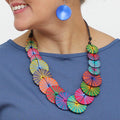 Colorful necklace with circular patterns worn by a person against a white background