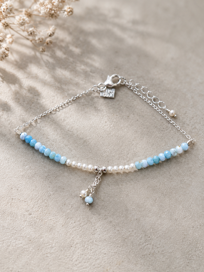 Light blue gemstone and freshwater pearl bracelet featuring delicate white pearls, soft blue beads and sterling silver accents on an adjustable design. A beach-inspired bracelet handcrafted for effortless coastal style.