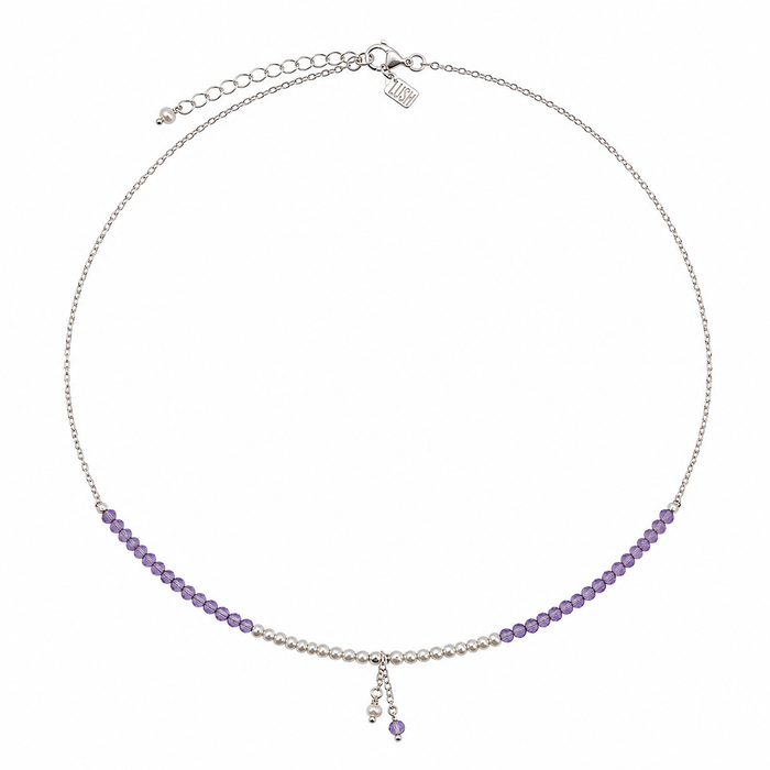 A delicate silver chain necklace featuring a curved row of small purple beads on each side, with a central section of white pearls and a dangling charm, shown on a plain white background.