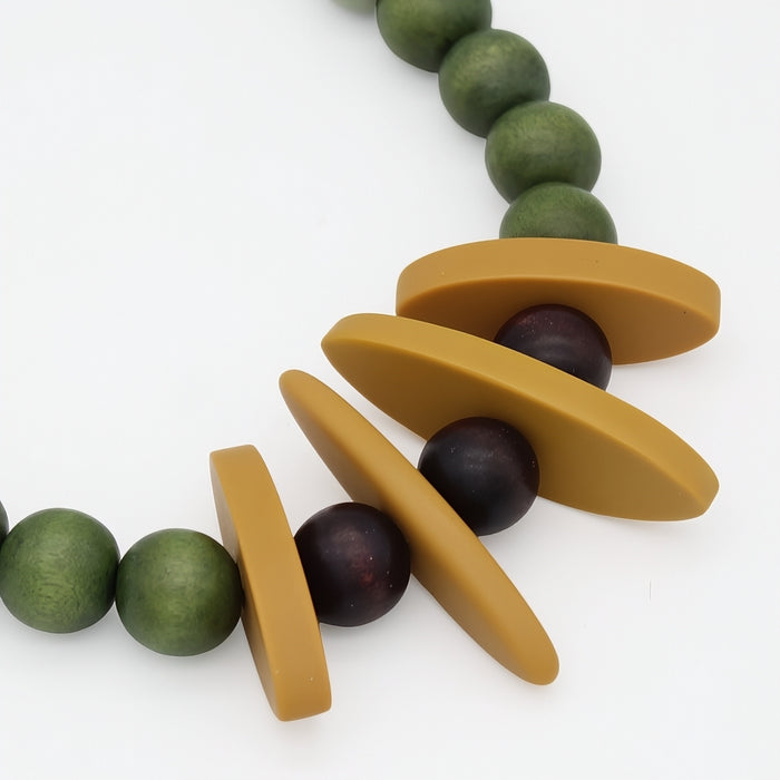 Close view of mustard resin accents and wood beads on green statement necklace