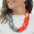 Person wearing a colorful necklace and earrings on a white background