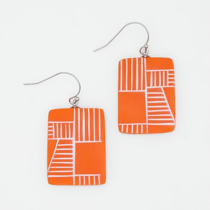 Orange earrings with white geometric patterns on a light gray background