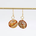 Pair of gold earrings with round, marbled brown and beige stones on a white background
