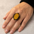 Hand wearing a ring with wood inlay on a neutral background