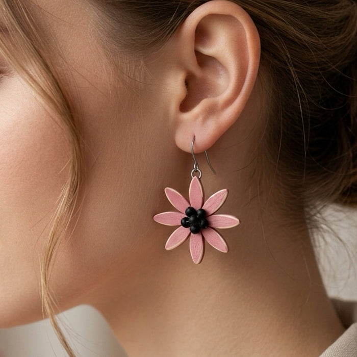 Close-up of a woman wearing pink flower earrings with a blurred floral background