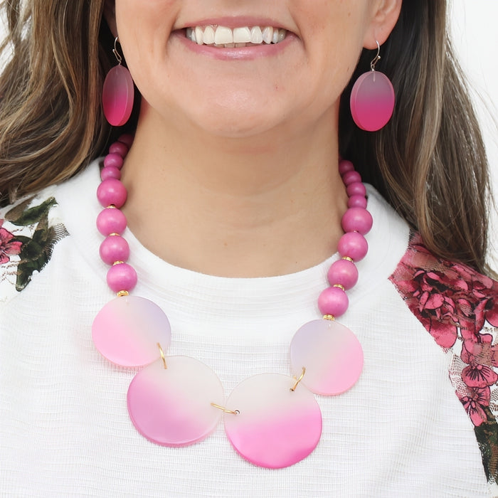 Woman wearing a pink beaded necklace and earrings on a white background