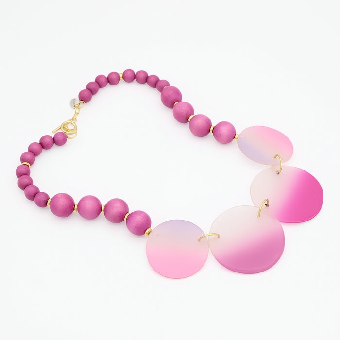 Necklace with pink beads and gradient pink pendants on a white background