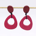 Pair of pink earrings with red tops on a white background