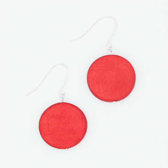 A pair of dangle earrings featuring round, matte red discs suspended from thin silver fishhook wires, set against a clean white background.